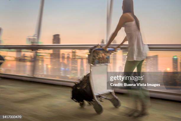 woman with luggage cart in the airport - dubai international airport stock pictures, royalty-free photos & images