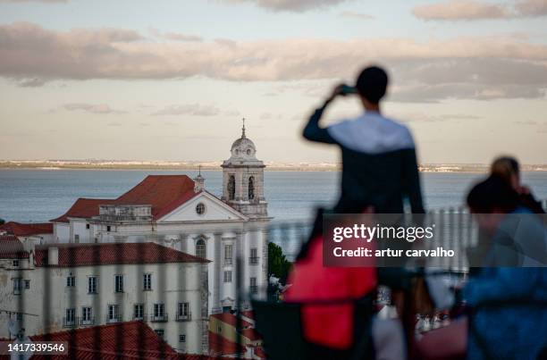 tourists enjoying the sunset hour in lisbon by the river. - zuid europa stockfoto's en -beelden