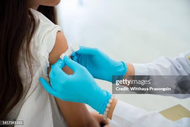 doctor applies bandage to preteen girl's arm following an immunization - vaccine bandage stock pictures, royalty-free photos & images