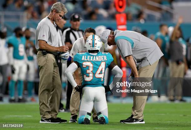 Mackensie Alexander of the Miami Dolphins talks with trainers after an injury during the second half against the Las Vegas Raiders at Hard Rock...