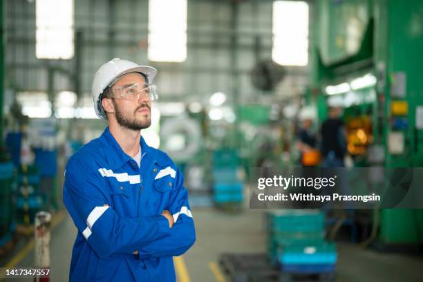 portrait of manual man worker is standing with confident with blue working suite dress and safety helmet - trabajador manual stock pictures, royalty-free photos & images