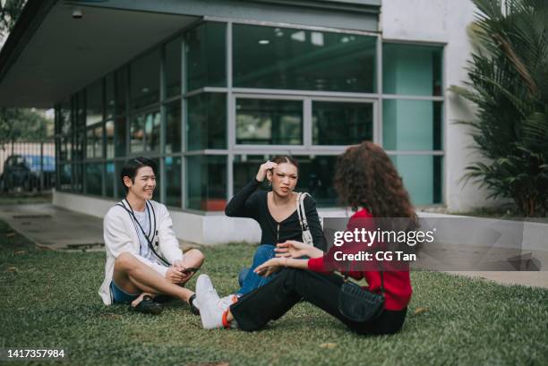 3 asian lgbtqia college students talking at campus outdoor after class sitting on ground - gender fluid stock pictures, royalty-free photos & images
