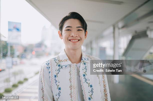 asian lgbtqia gay person looking at camera smiling on bridge in city - nb stock pictures, royalty-free photos & images