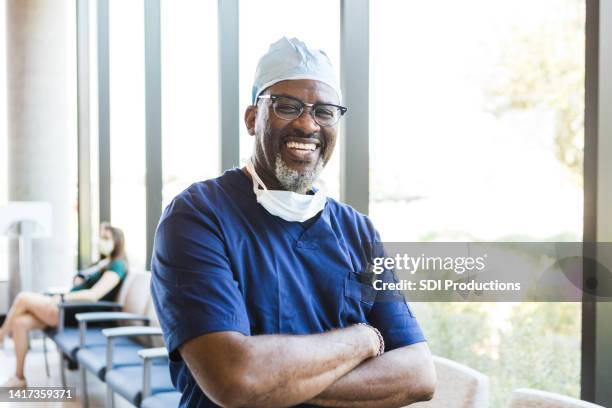 doctor stands and crosses his arms for a headshot photo - surgeon stock pictures, royalty-free photos & images