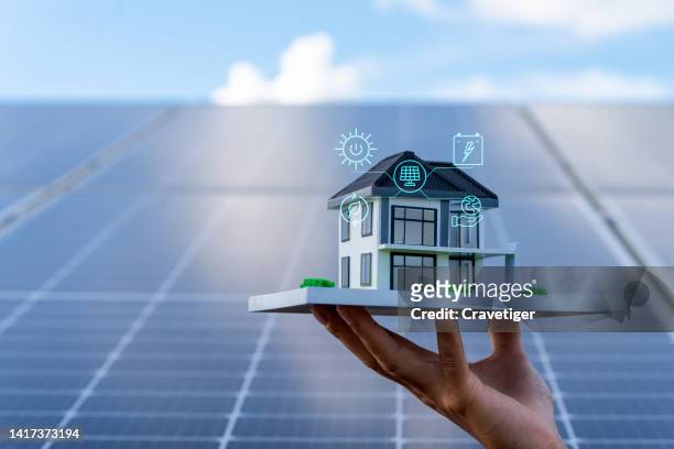 an architectural model with solar panels . concept energy saving and sustainable resource . the model of house lift by hand on the solar panel with digitization display , photovoltaic against with sun  light and reflex on solar panel . - solar equipment stock-fotos und bilder