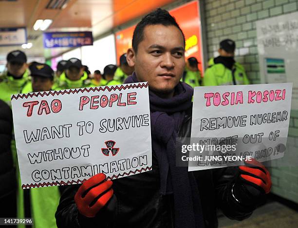 Man holds up placards calling for the removal of nuclear waste from Lanyu island off the shores of Taiwan during a rally by protesters from various...