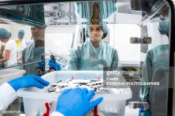 female employees in a pharmaceutical industry seen while one is taking over the box with blister packs from the other just after manufacturing process - hygiene stock pictures, royalty-free photos & images