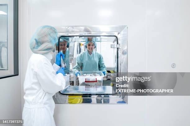 weibliche mitarbeiter in einer pharmaindustrie gesehen, während einer die box mit blisterpackungen von der anderen kurz nach dem herstellungsprozess übernimmt - arzneimittelherstellung stock-fotos und bilder