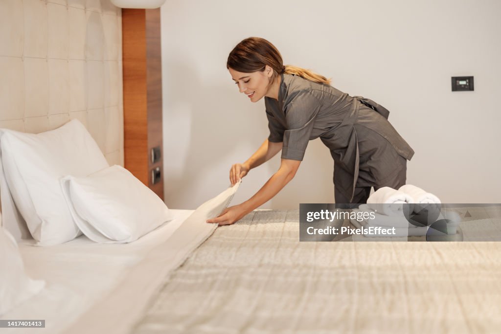 Empregada que faz a cama em um hotel
