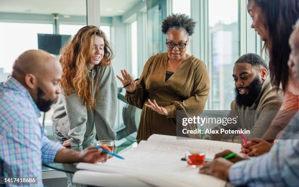 liderazgo femenino. mujer afroamericana liderando reunión de negocios. colegas creativos multirraciales que tienen una reunión en la oficina moderna. - differing abilities female business fotografías e imágenes de stock