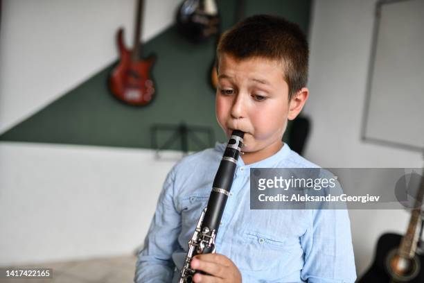 focused boy blowing air into clarinet in classroom - airboard stock pictures, royalty-free photos & images