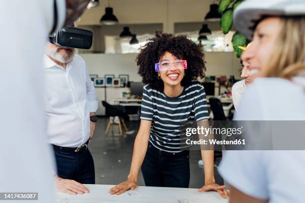 happy businesswoman wearing smart glasses discussing with colleagues in office - ウェアラブルコンピュータ ストックフォトと画像