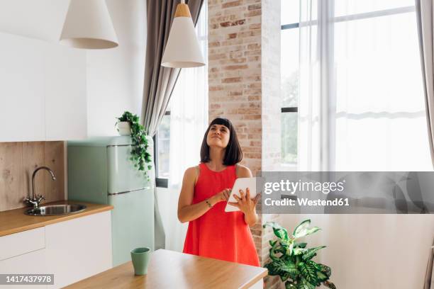 woman using home automation in kitchen at home - pendant light stock pictures, royalty-free photos & images