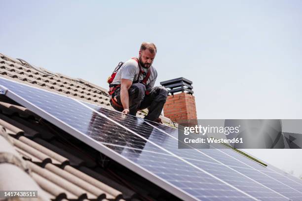 technician installing solar panels on rooftop - pannello solare foto e immagini stock