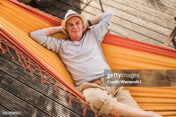senior man wearing hat relaxing in hammock - hängematte stock-fotos und bilder
