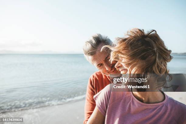 happy couple having fun at beach on sunny day - 50 54 jahre stock-fotos und bilder