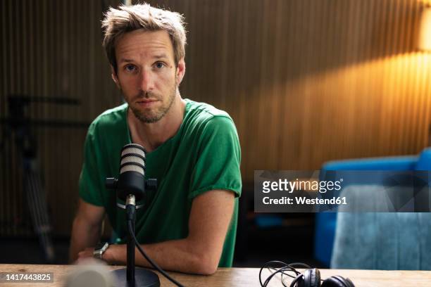 radio dj with microphone sitting in recording studio - radio presenters stock pictures, royalty-free photos & images