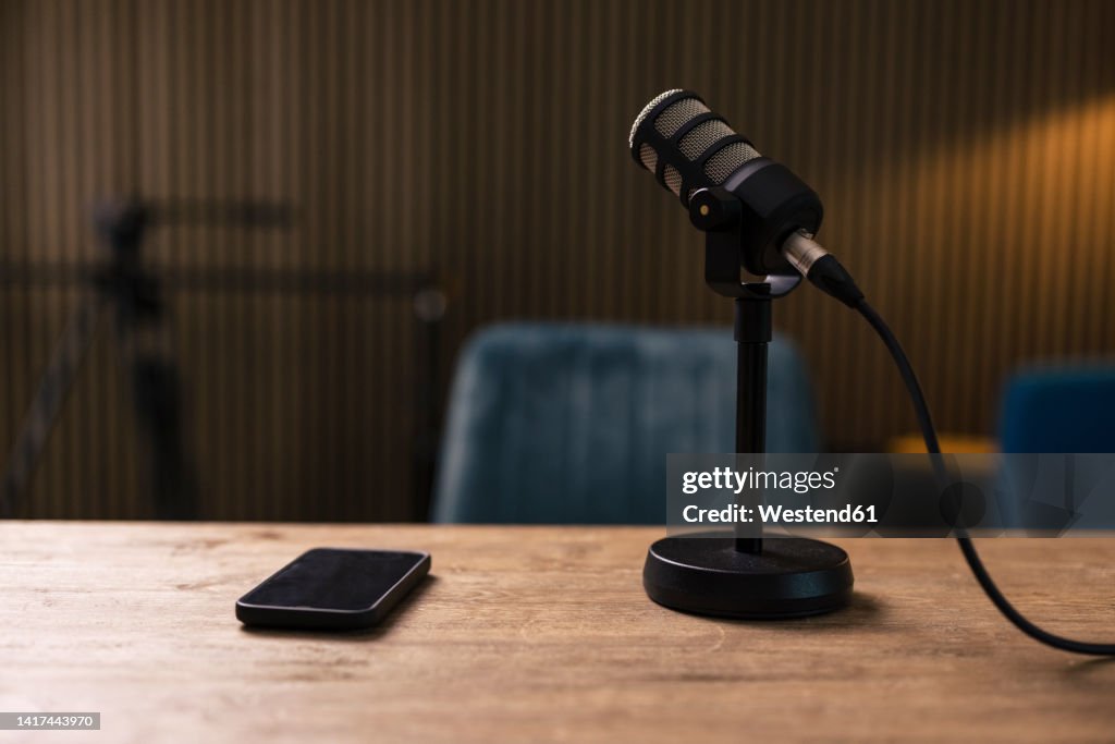 Smart phone by microphone on desk in recording studio