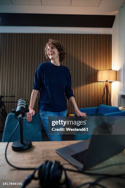 cheerful radio dj standing amidst chair in recording studio - front flash photography foto e immagini stock