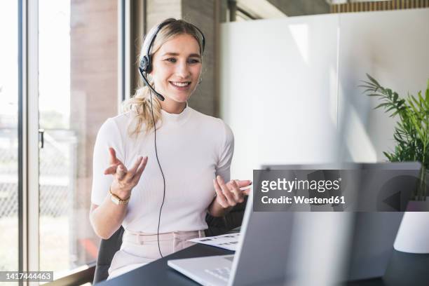 customer service representative gesturing on video call through laptop in office - zoom business meeting stock pictures, royalty-free photos & images
