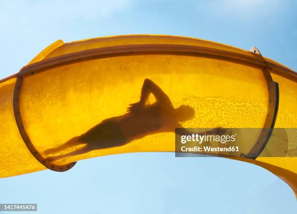 silhouette of person sliding down water slide - tobogán de agua fotografías e imágenes de stock