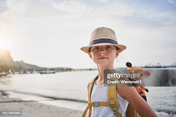 smiling girl with stuffed toy in bag at beach - very young thai girls stock pictures, royalty-free photos & images