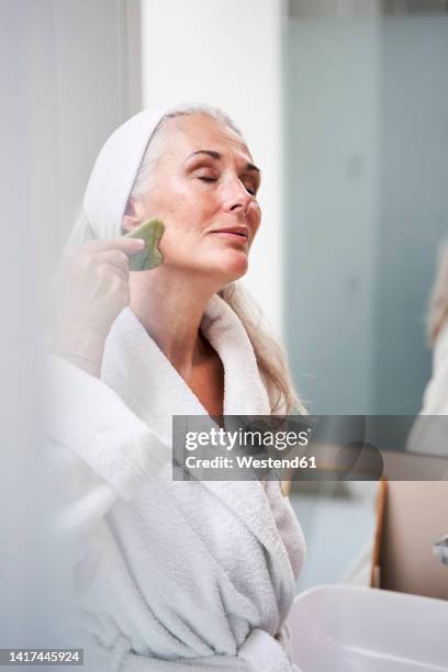 beautiful woman massaging with jade stone in bathroom - spooning stock pictures, royalty-free photos & images