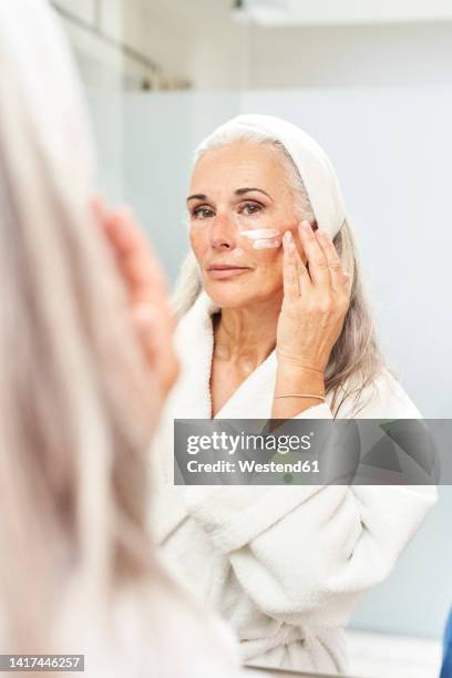 reflection of woman applying face cream - applying stock pictures, royalty-free photos & images