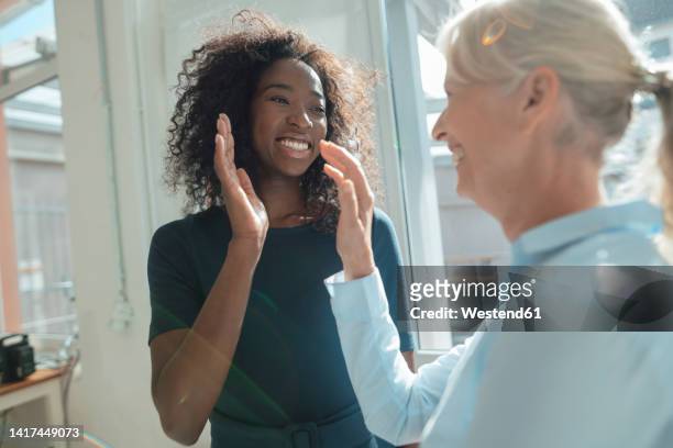 smiling businesswoman giving high-five to colleague in office - super sensory stock-fotos und bilder