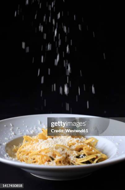 studio shot of grated parmesan pouring on plate of pasta - grated stock pictures, royalty-free photos & images