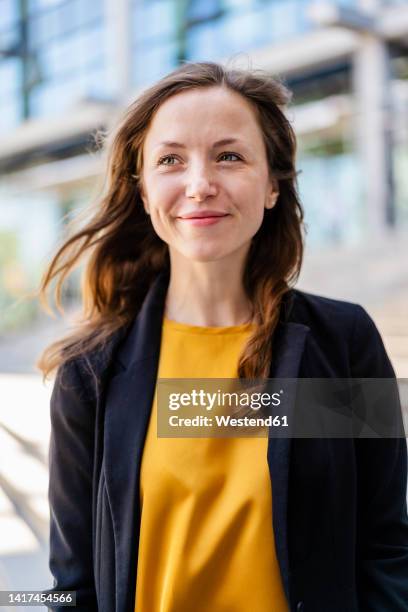 smiling businesswoman with brown hair wearing blazer - woman 30 outside stock-fotos und bilder