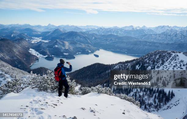 hiker photographing walchensee and bavarian prealps from mt. herzogstand, bavaria, germany - mt herzogstand bildbanksfoton och bilder