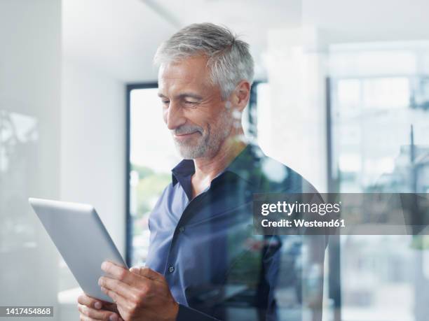 smiling mature businessman using tablet pc in office - westend61 fotografías e imágenes de stock