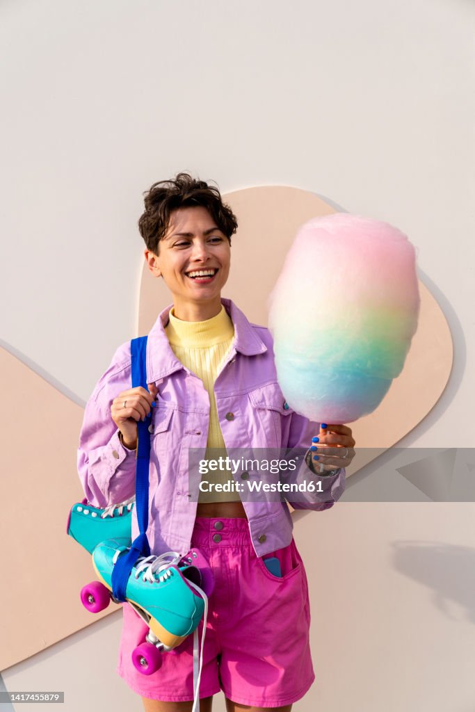 Happy woman with roller skates holding cotton candy