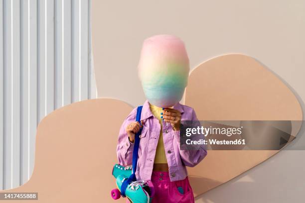 woman covering face with cotton candy in front of wall - cotton candy stock-fotos und bilder