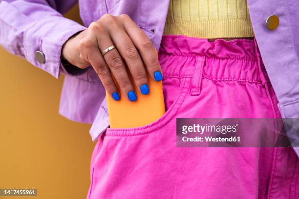 woman removing mobile phone from pocket - ficka bildbanksfoton och bilder
