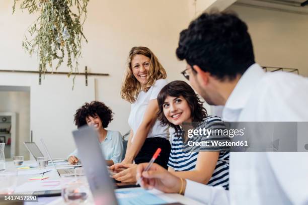 happy businesswomen looking at colleague in office - rodada de classificação - fotografias e filmes do acervo