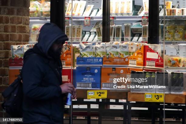 Man walks past a Woolworths supermarket on York Street on August 24, 2022 in Sydney, Australia. Supermarket chains Woolworths and Coles will announce...