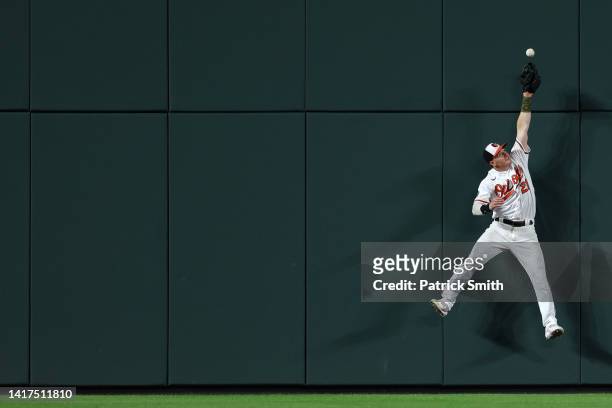 Austin Hays of the Baltimore Orioles cannot make a catch on a hit by Luis Robert of the Chicago White Sox during the seventh inning at Oriole Park at...