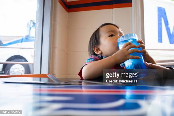 a little boy is about to drink water from a large adult glass. - ハワイ stock-fotos und bilder