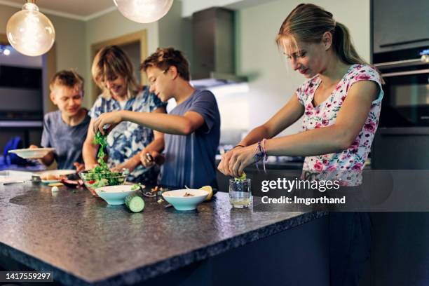 kinder im teenageralter helfen der mutter, das mittagessen in der küche zuzubereiten - kids dressing up stock-fotos und bilder