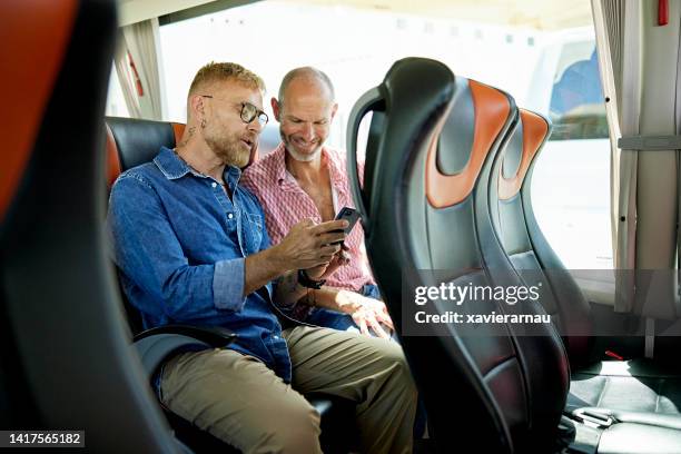 gay couple using smart phone before departure on motor coach - coach bus stock pictures, royalty-free photos & images