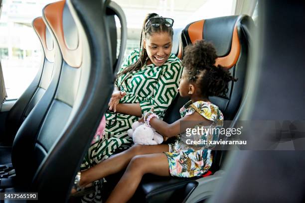 Mother laughing at young daughter making a face on bus trip