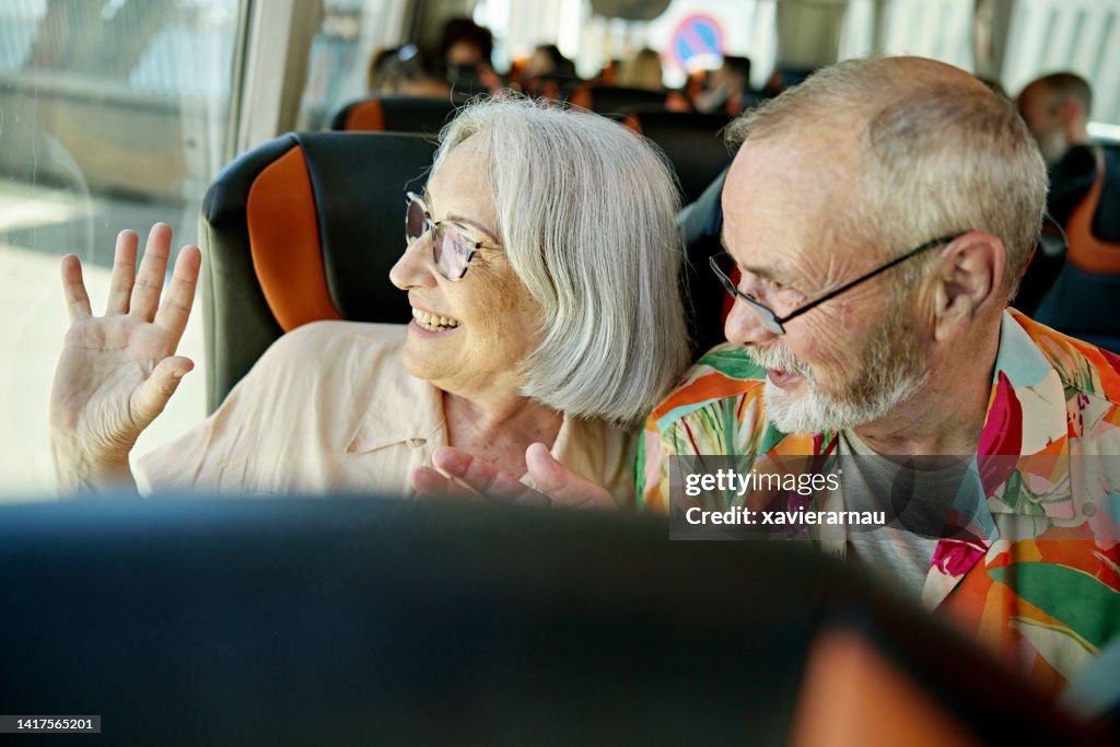 Älteres Paar winkt Freunden vor der Abfahrt des Busses zu