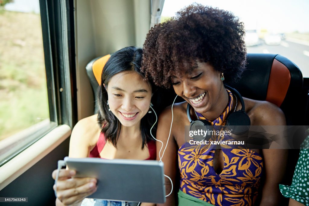 Chinesische und schwarze Urlauber, die auf einer Busreise Technologie teilen