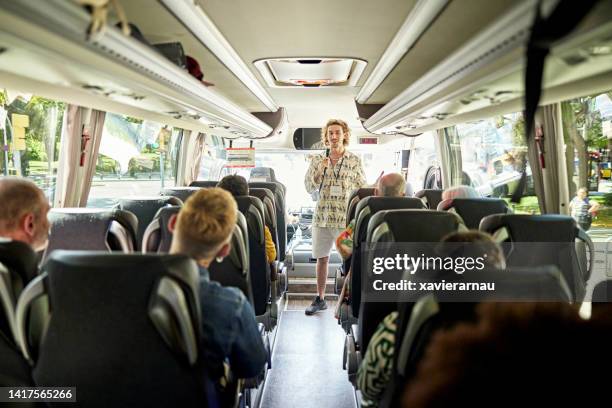 busreiseleiter, der mit dem mikrofon mit den passagieren spricht - coach bus stock-fotos und bilder