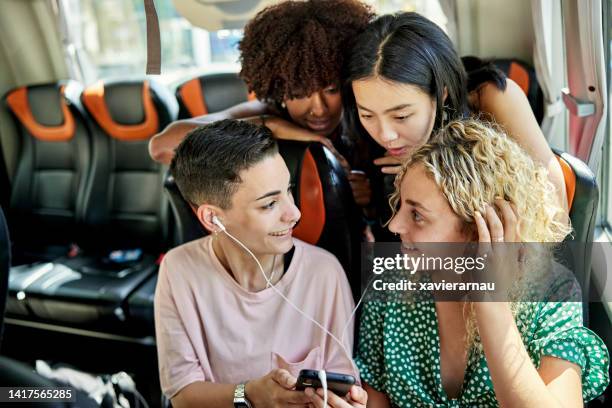 young vacationers enjoying technology onboard travel coach - sharing headphones stock pictures, royalty-free photos & images