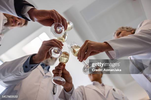 diverse multiracial group of doctors celebrating with champagne - alcohol medical stock pictures, royalty-free photos & images