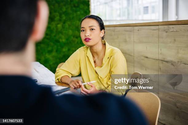 office manager talking to colleague at her desk - yellow blouse stockfoto's en -beelden