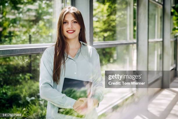 portrait of woman standing in hallway with glass window panes - green shirt stock pictures, royalty-free photos & images